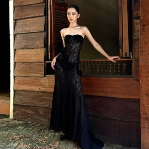 Detail of black lace tube dress with 3D floral accents and elegant floor-length hem