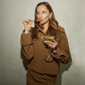 Detail of a brown short jacket suit set featuring shell earrings and a leather watch
