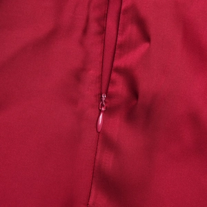 Dettaglio macro della cerniera invisibile su tessuto di raso rosso vino liscio