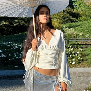Détail du haut en satin blanc à col en V avec lien à la taille et jupe à paillettes