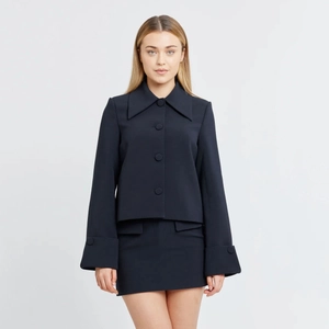 Detail of navy blue two-piece set featuring large pointed lapel and matching buttons