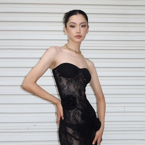 Detail of elegant black lace tube dress featuring 3D floral accents and open back design