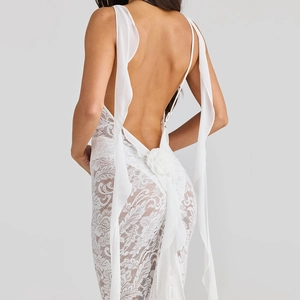Vue détaillée d'une robe en dentelle blanche avec fleur 3D et rubans en mousseline au dos