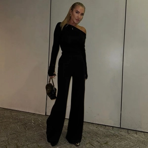 Detail of elegant black one-shoulder long sleeve top and high-waisted wide leg pants set