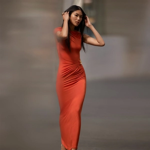 Detail of elegant orange maxi dress showing ruched waist and side gold buckle accent