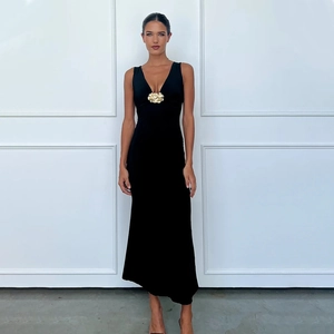 Détail d'une robe noire élégante à col en V avec une boucle florale en métal doré