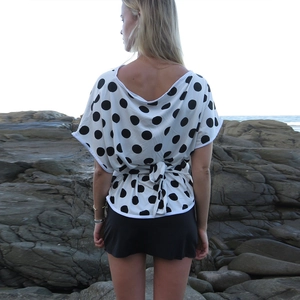 Polka dot short sleeve top for women with back V-neck and tie-waist in outdoor beach setting