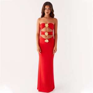 Detalle del vestido rojo sin espalda con tres cortes horizontales y hebillas de flores de oro