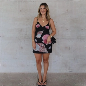 Detail of black mini dress featuring a vibrant seashell print and thin spaghetti straps