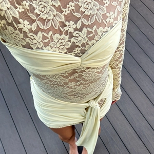 Detail of light green floral lace top and ruched bodycon dress on wooden deck
