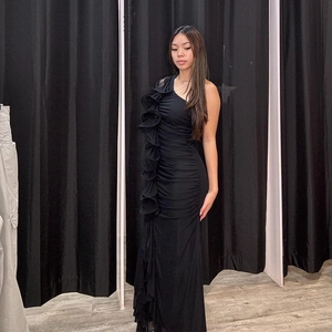 Close-up of elegant ruffles and side ruching on the black one-shoulder evening dress