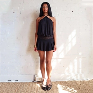 Detail of black halter neck dress featuring delicate lace patchwork and ruffled hemline