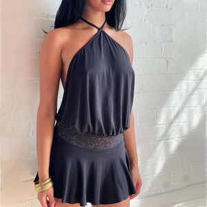 Detail of black halter dress featuring delicate lace waist cutout and ruffled skirt hemline