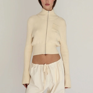 Detail of cream rib-knit cardigan featuring silver zipper and cozy mock neck texture