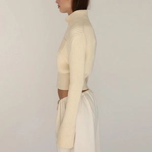 Detail of cream ribbed knit sweater showing high neck design and short cropped fit