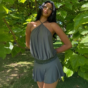 Close-up of olive green satin halter set featuring delicate lace trim and ruched skirt detail