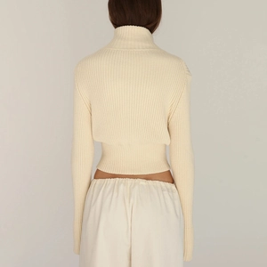 Detailed back view of a cream ribbed knit turtleneck sweater with cropped waist and long sleeves