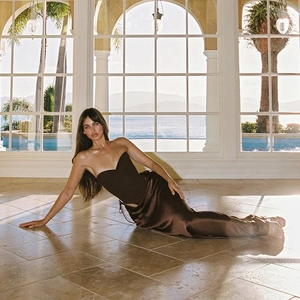 Detailed view of deep brown satin mermaid skirt with elegant drape and glossy finish