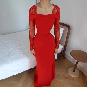 Détail des manches en dentelle rouge et col bardot sur robe de soirée moulante