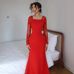 Détail d'une robe de soirée rouge élégante avec manches en dentelle et coupe sirène ajustée
