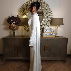 Detail of elegant white satin evening gown with high collar and sweeping floor tail
