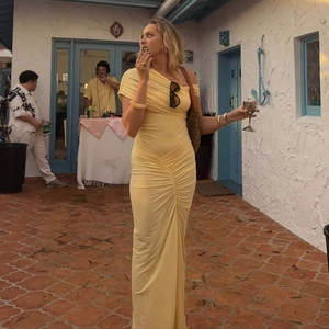 Detailed view of yellow ruched mesh midi dress with slit on a mediterranean patio
