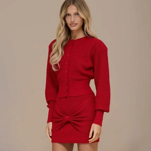Detail of red knit two-piece set featuring front buttons and a large 3D waist bow decoration