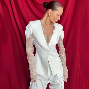 Detailed view of white blazer featuring deep V-neckline and intricate floral lace patchwork