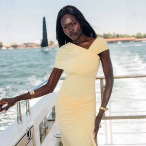 Detail of light yellow ruched fabric and off-shoulder asymmetrical neckline on bodycon dress