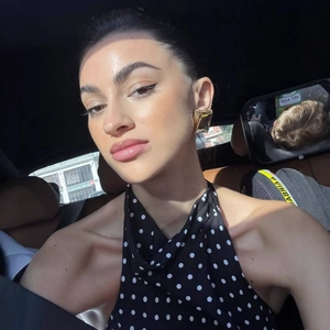 Detailed view of polished gold rectangular earrings paired with a polka dot halter dress