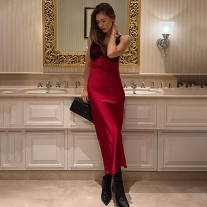 Elegant red satin midi dress with black lace trim and open back, worn in luxury interior