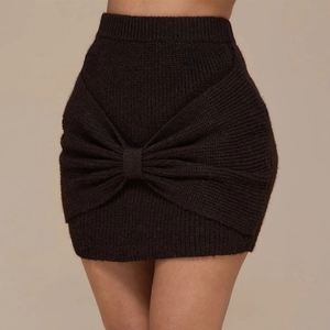 Detail of high-waist black knit mini skirt featuring a large decorative front bow