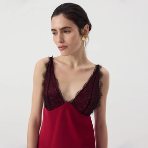 Close-up of red satin dress with black lace trim and intricate deep V-neckline detail
