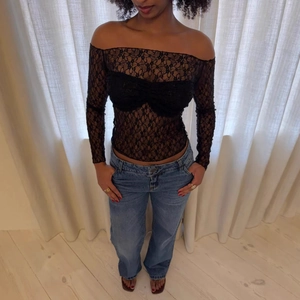 Sexy black lace off-shoulder long sleeve crop top paired with classic blue denim jeans