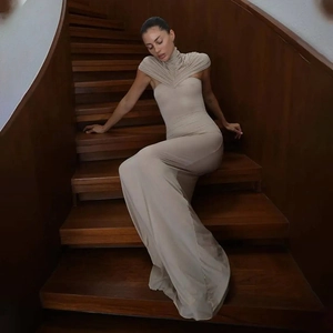 Detailed view of elegant pleated turtleneck design on a beige floor-length bodycon dress