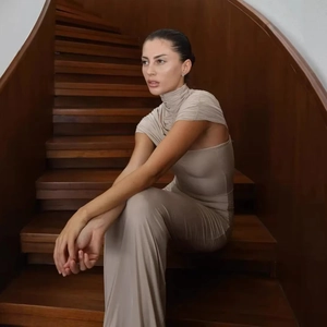 Detail of elegant beige mock neck dress with draped ruched fabric on luxury stairs