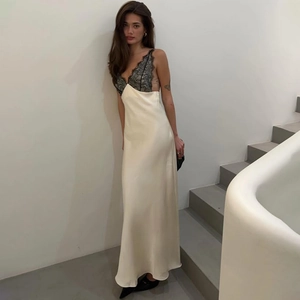 Detailed close-up of the black lace trim on a cream satin backless maxi dress