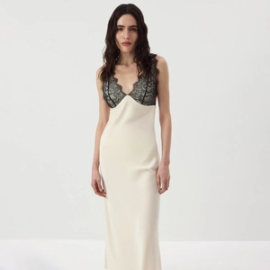Detail view of cream satin maxi dress featuring intricate black lace trim on the V-neckline