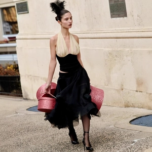 Halter neck top with black waist skirt and feather headpiece in street setting