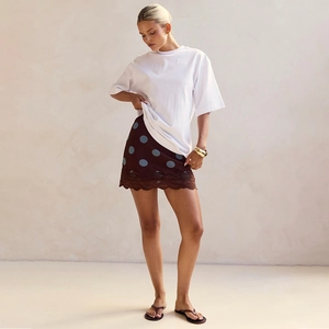 Detail of a brown polka dot mini skirt featuring dark lace trim and white T-shirt styling