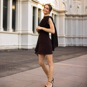 Detail of deep brown sleeveless mini dress with draped cowl neck and long streamers