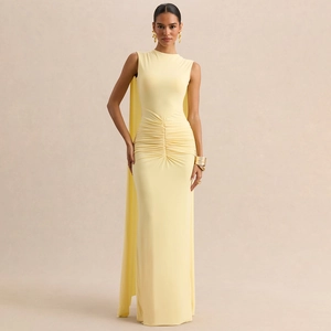 Detail of elegant pale yellow maxi dress featuring slim fit waist pleats and long cape