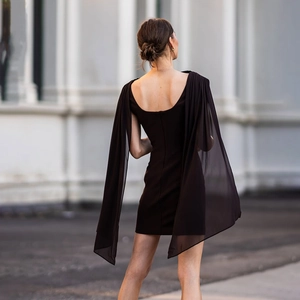 Detailed back view of a slim black mini dress with elegant long sheer cape draping