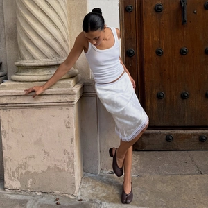 Dettaglio gonna midi in raso bianco con bordo in pizzo e canotta a coste slim