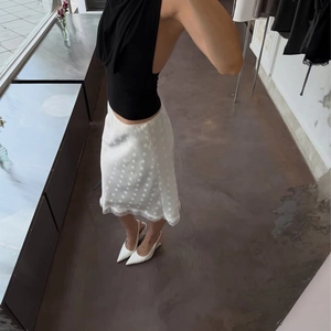 Dettaglio gonna midi bianca a pois con bordo in pizzo delicato e design a vestibilità slim
