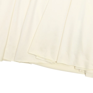 Detailed macro view showing the pleated fabric texture and hem of the beige dress