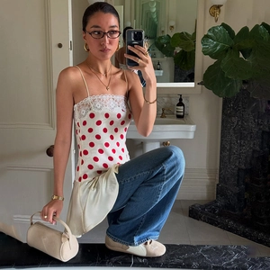 Detail des weißen Polka-Dot-Camisoles mit roten Punkten und feiner Spitze am Ausschnitt