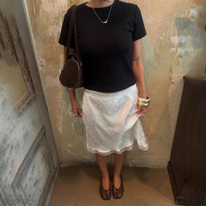 Dettaglio gonna midi in raso bianco con jacquard a pois e bordo in pizzo elegante