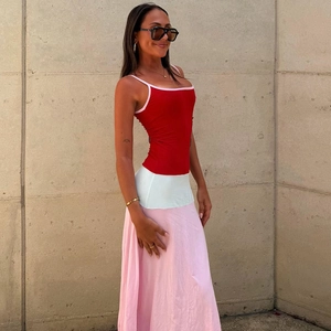Detail of color-block patchwork long dress featuring a red bodice and pale pink hemline