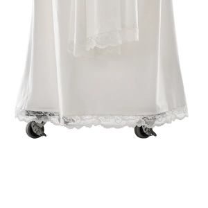 Detail showing elegant lace hem and silky white satin fabric of the long fitted dress